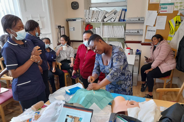 lady demonstrating catheter insertion to a group of students